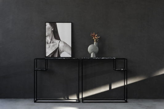 Black-and-white framed artwork displayed above a minimalist black console against a dark wall
