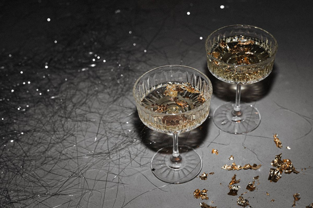 Two elegant glasses with gold flakes on a dark table, symbolizing the end of the year.